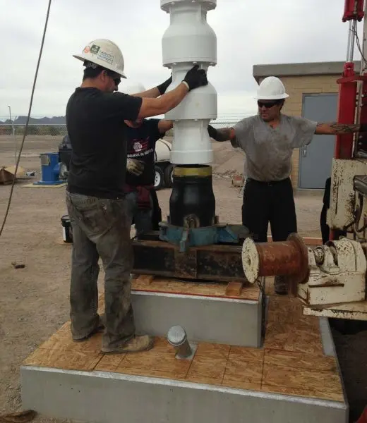 Group of men setting up well drilling machine